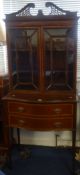 An Edwardian mahogany display cabinet, with swan neck pediment, two cabinet doors over a