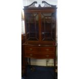 An Edwardian mahogany display cabinet, with swan neck pediment, two cabinet doors over a