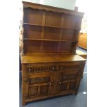 A traditional oak dresser, in two parts with upper open shelves, the base fitted with drawers and