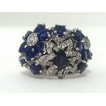 A fancy diamond and sapphire flower ring, finger size N.