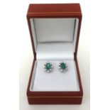 A pair of emerald and diamond cluster earrings set in white gold.