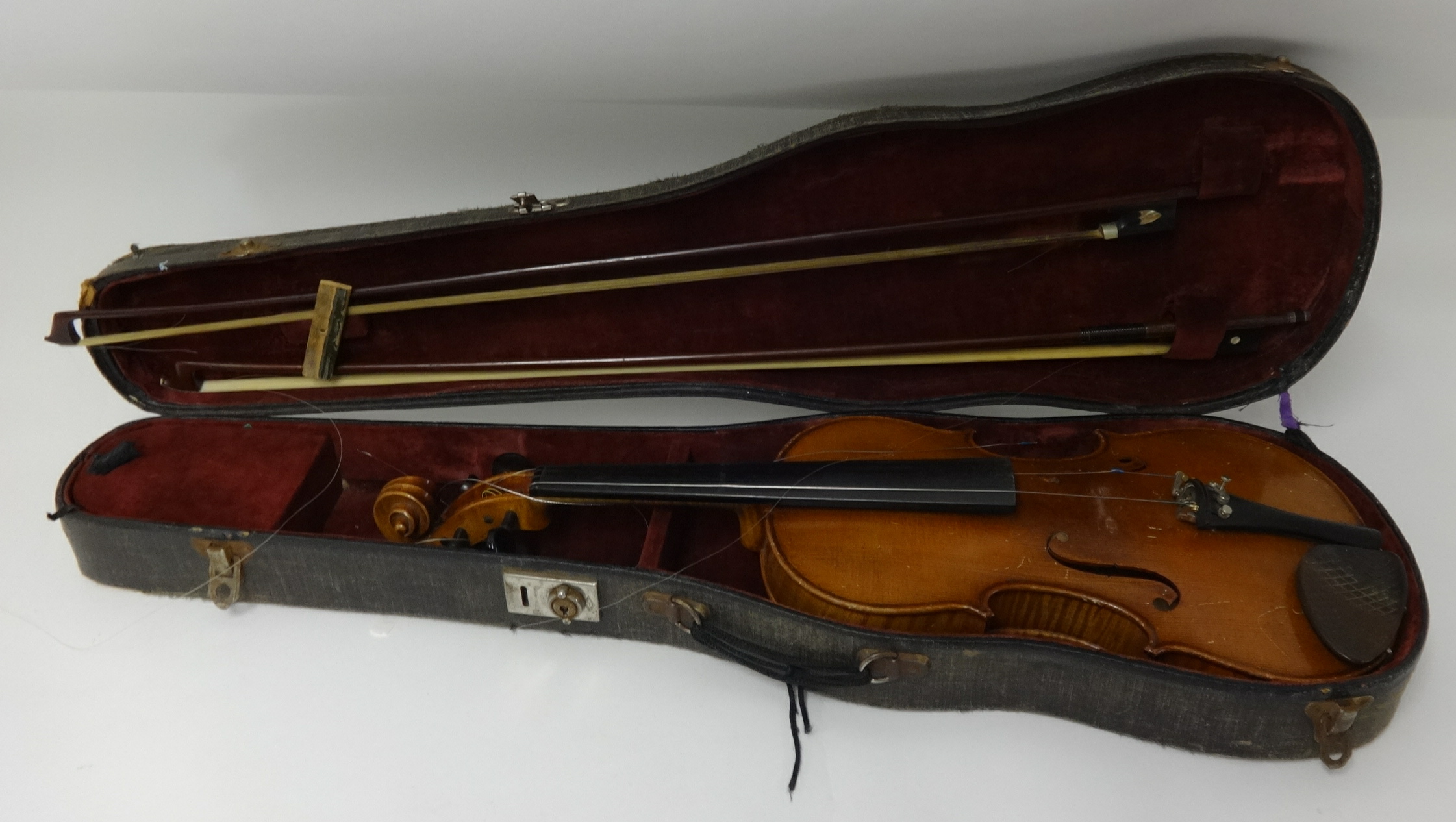 An old violin and two bows, cased.