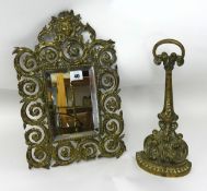 A 19th century brass door stop and a small wall mirror in an ornate brass frame.