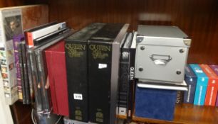 A collection of Queen CDs and books.