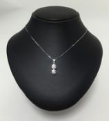 A 14ct white gold pendant set with two diamonds in target style setting on a fine chain.
