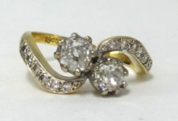 An 18ct gold crossover ring set with two old cut diamonds, approx .50 carats total, further diamonds