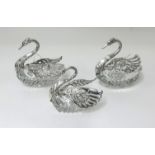 A set of three Continental silver and cut glass sweet meat dishes, modelled as swans (3).