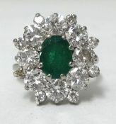 An 18ct white gold diamond and emerald cluster ring, having an oval cut emerald approx 1.00ct,