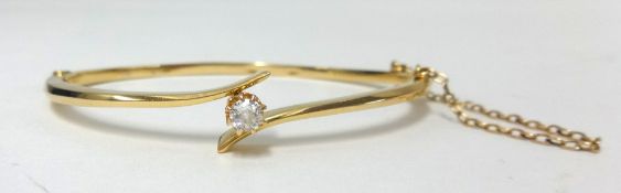 An 18ct yellow gold bangle set with a single round cut diamond, approx 7.60gms.