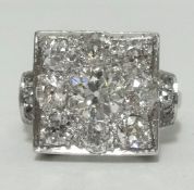 An impressive platinum and diamond set ring, of square form set with 9 diamonds, the centre stone