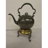 A large pewter kettle on a hinged fitting to a brass and pewter stand, the kettle with two belt