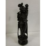 Carved dark wood figure of a robed Far Eastern woman carrying bundle on her shoulder, her robe