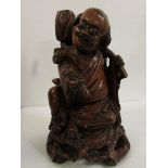 Carved red wood figure of seated Chinese man with shoulder burden and holding ruyi sceptre (height
