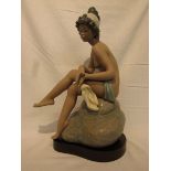 A Lladro stoneware figure of nude ballerina seated on stone and holding ballerina shoes, blue