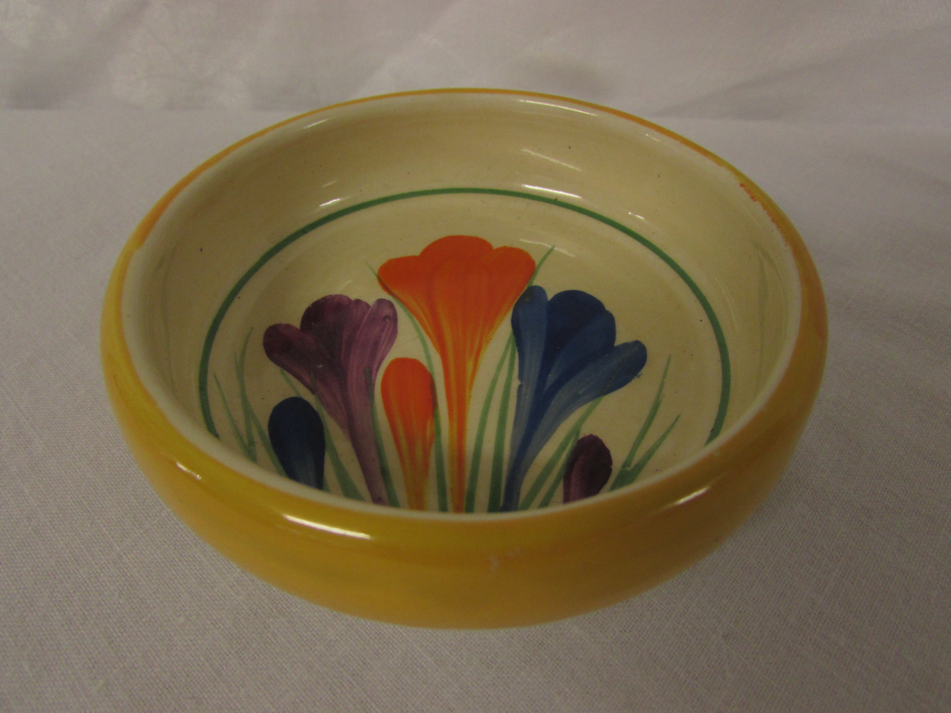 Bizarre by Clarice Cliff crocus circular dish, yellow rim, diameter 9.3cm, black transfer mark to