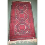 A blue and red ground three medallion rug with repeating stylized foliate patterning to the three