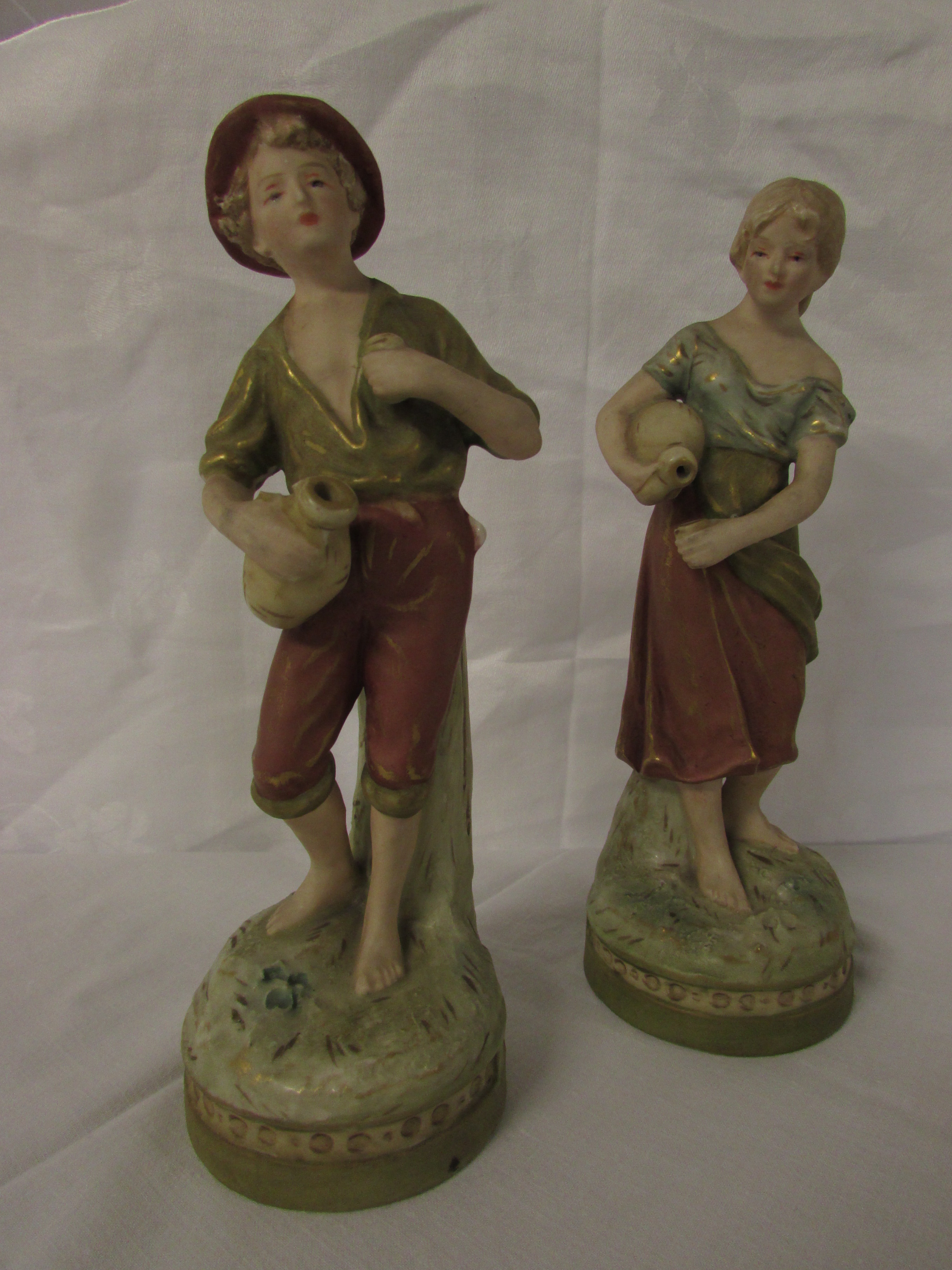 Two corresponding Royal Dux figures of young man and woman with flasks and drinking cups, on