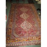 An early 20th century Shiraz Persian carpet, predominately red ground with three medallions in three