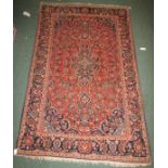 A Persian Kashan rug with a deep pink ground and central floral emblem with overall foliate