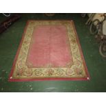 A pink ground Indian rug with a large cream margin of wreathen floral design (290cm x 220cm)