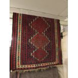 A course hand woven blue and red ground rug of Shiraz appearance with three margins and six