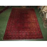 A good quality 20th century Afghan Kunduz red ground machine made rug with twelve small margins,