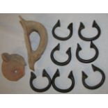 Seven bronze torcs / slave manillas (each about 6cm diameter), a pottery handle fragment, and a