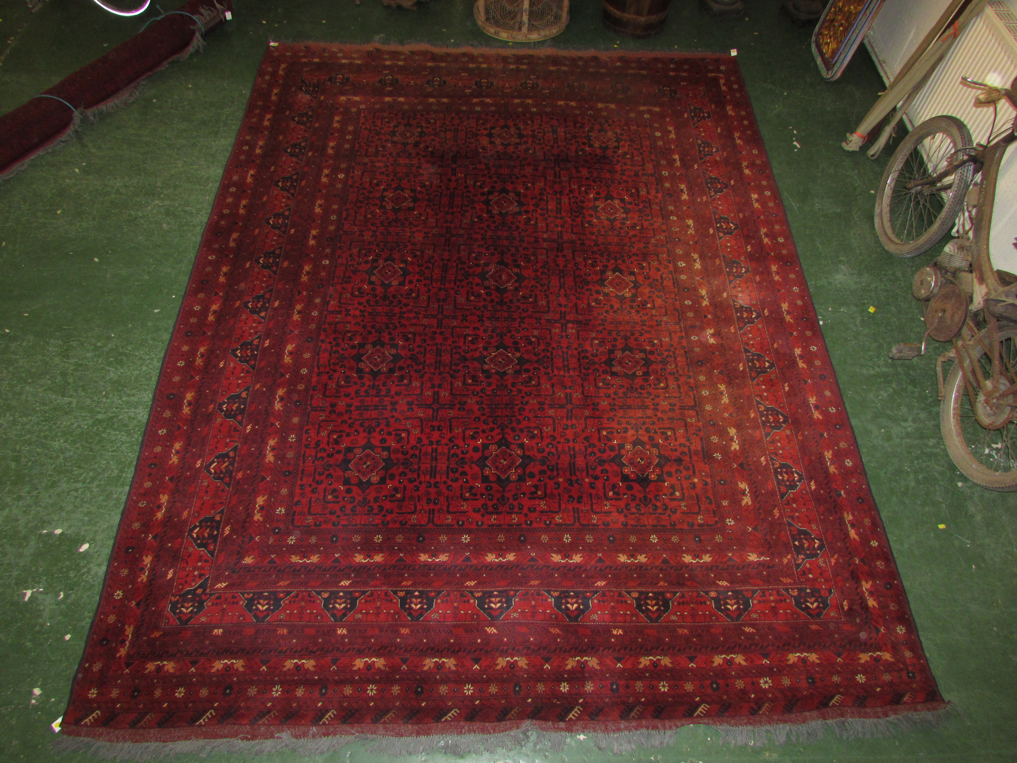 A good quality 20th century Afghan Kunduz red ground machine made rug with twelve small margins,