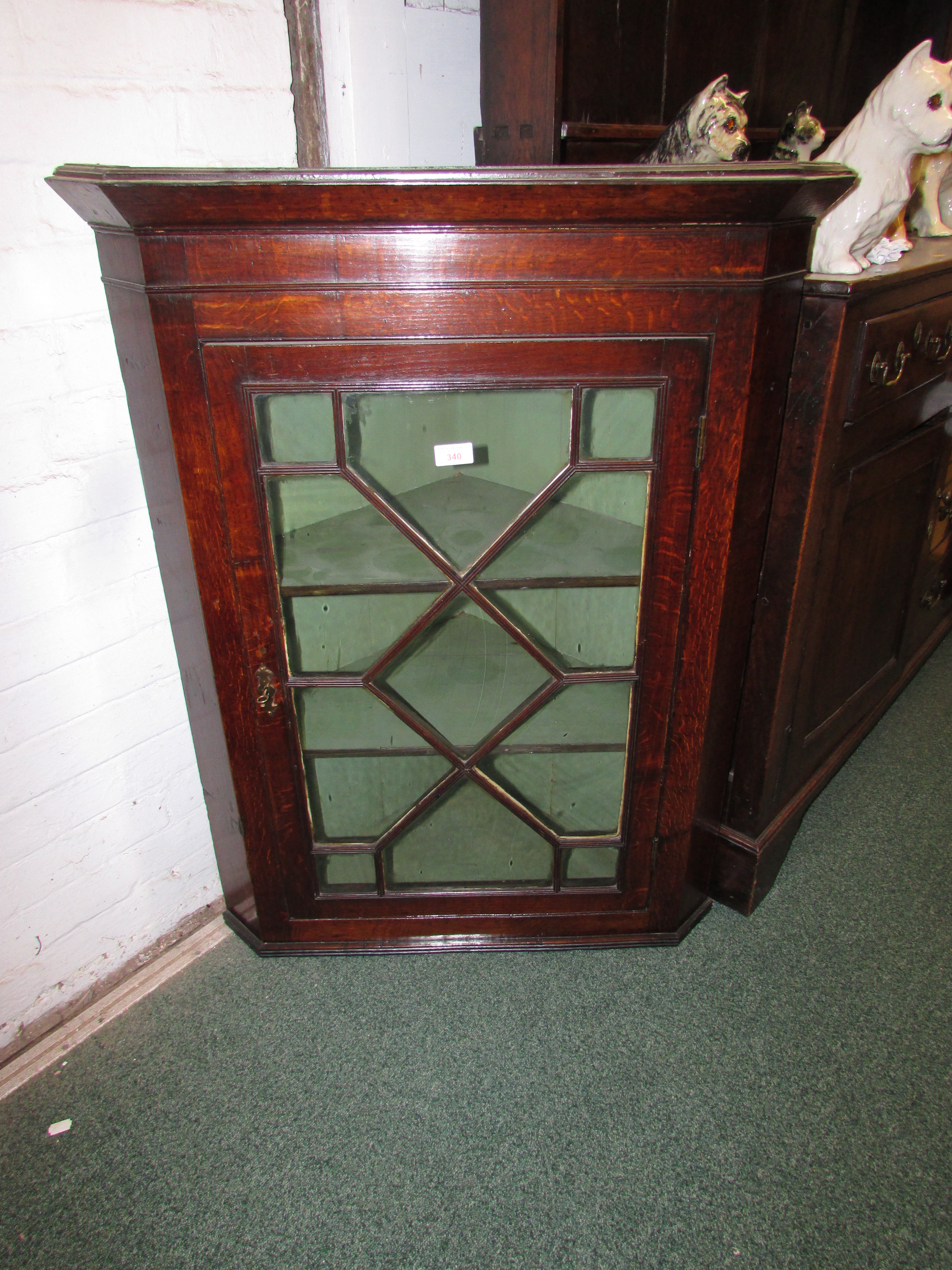 George III oak corner wall cupboard with geometrically glazed door with two shelves within, key in