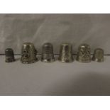 SIX METAL THIMBLES - a child's with basic chased decoration and no assay marks (1.7cm), one small