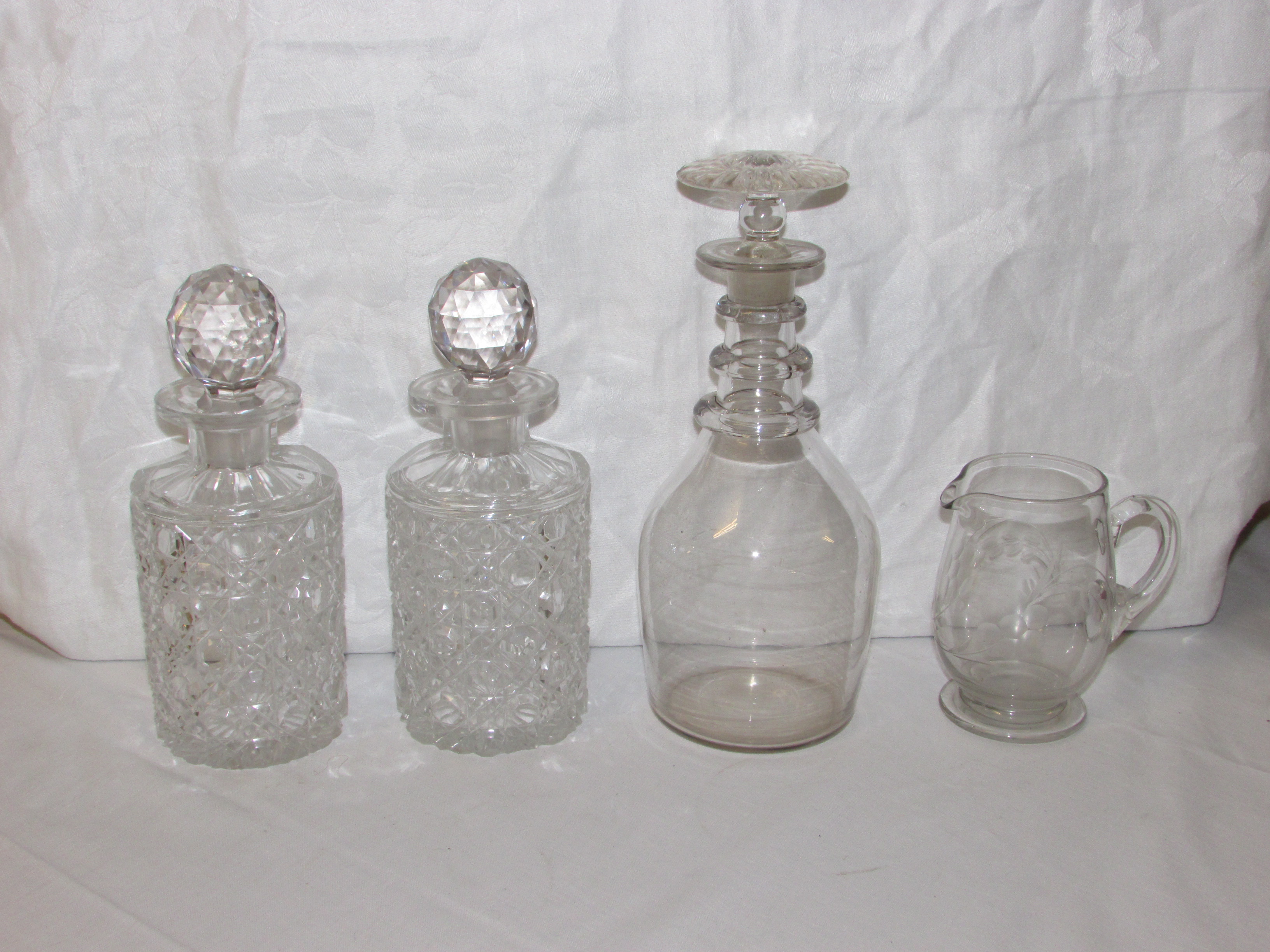 Two heavily cut glass spirit decanters and stoppers, engraved glass milk jug and wine decanter