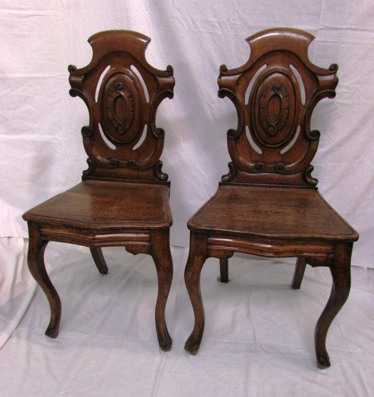 Pair of 19th century oak hall chairs with scrolled and pierced shield shaped backs with stylized