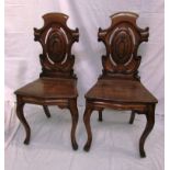 Pair of 19th century oak hall chairs with scrolled and pierced shield shaped backs with stylized