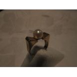 Gold ring stamped 14K, set with a cultured pearl in an indented setting and machined finish at the