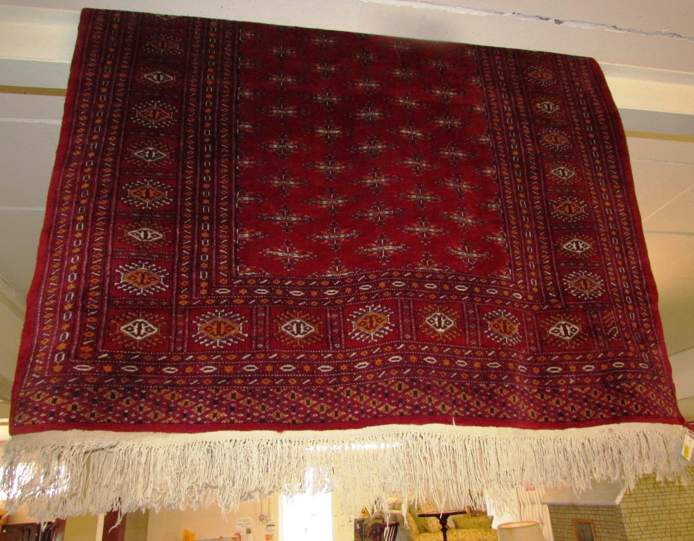 RED GROUND FLOOR RUG WITH EIGHT MARGINS AND TASSELLED ENDS