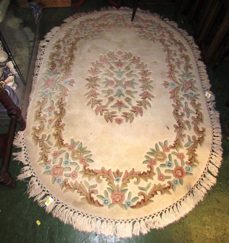 CREAM GROUND SHAPED FLOOR RUG WITH TASSELLED EDGE