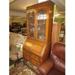 OAK BUREAU BOOKCASE WITH GLAZED AND LEADED DOORS TO TOP AND THREE DRAWERS TO STRETCHERED BASE (KEY