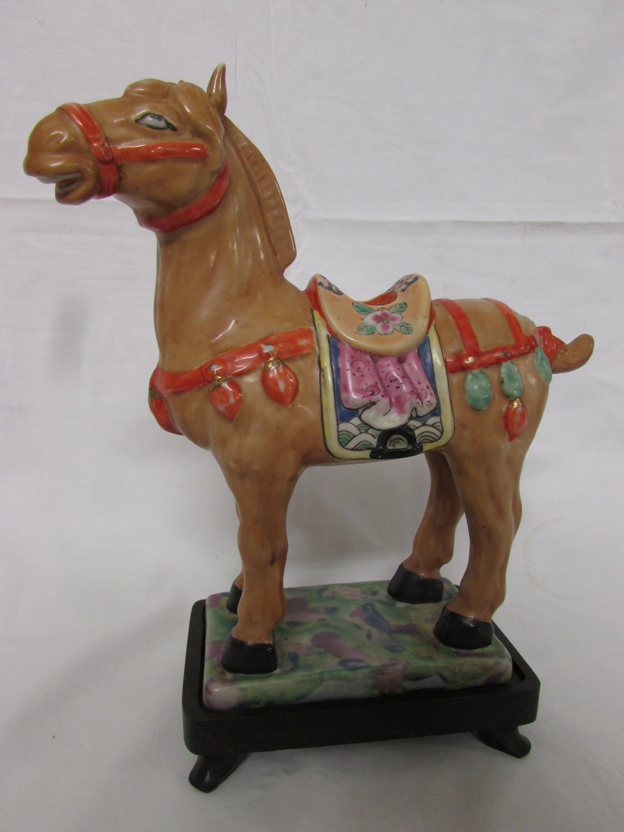 A porcelain figure of a standing brown horse with saddle and harness modelled in the archaic Chinese