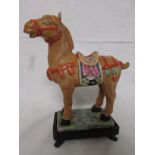 A porcelain figure of a standing brown horse with saddle and harness modelled in the archaic Chinese