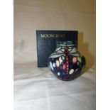 Moorcroft vase of squat form, green ground graduating to purple with piped decoration of three