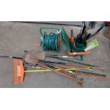 A collection of household tools including spades, rakes, saws ,