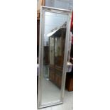 Tall free standing bevelled edge mirror with upholstered hall chair.