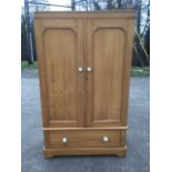 A Victorian pine wardrobe, having plain cornice above a pair of arched panelled doors mounted with