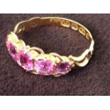 An 18ct gold pink sapphire ring, the five graduated stones of 1.56 carats, on pierced scrolled