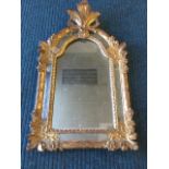 A nineteenth century Italian gilt mirror, with carved giltwood crest above an arched plate, the