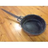 An antique copper pan with hammered rim, riveted to tapering hand-forged iron handle. (26in)