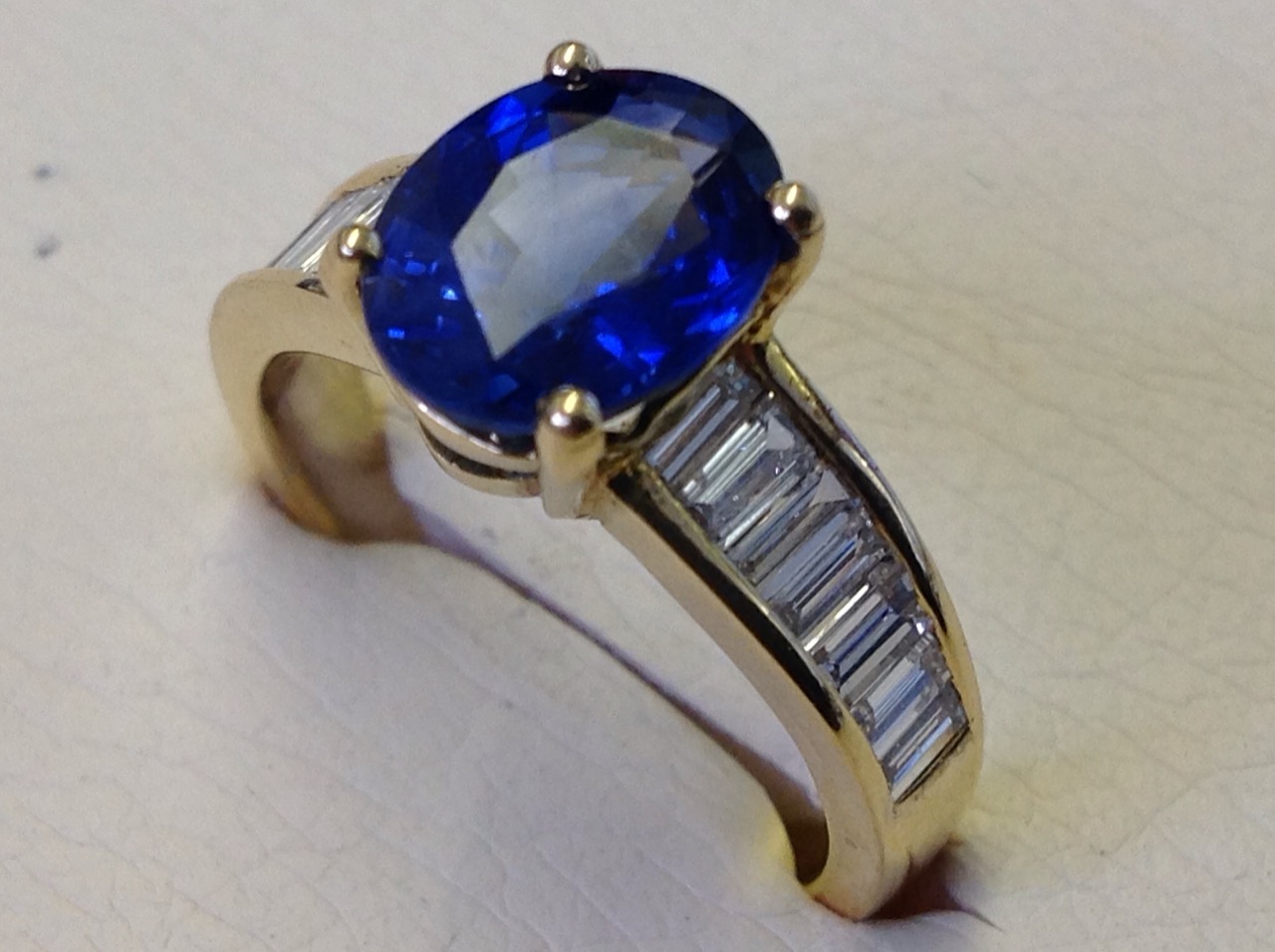 An 18ct yellow gold Madagascan oval sapphire & baguette cut diamond ring, the oval claw set sapphire