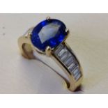 An 18ct yellow gold Madagascan oval sapphire & baguette cut diamond ring, the oval claw set sapphire