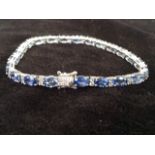 An 18ct sapphire & diamond bracelet, with twenty three claw set oval sapphires weighing 9.25 carats,