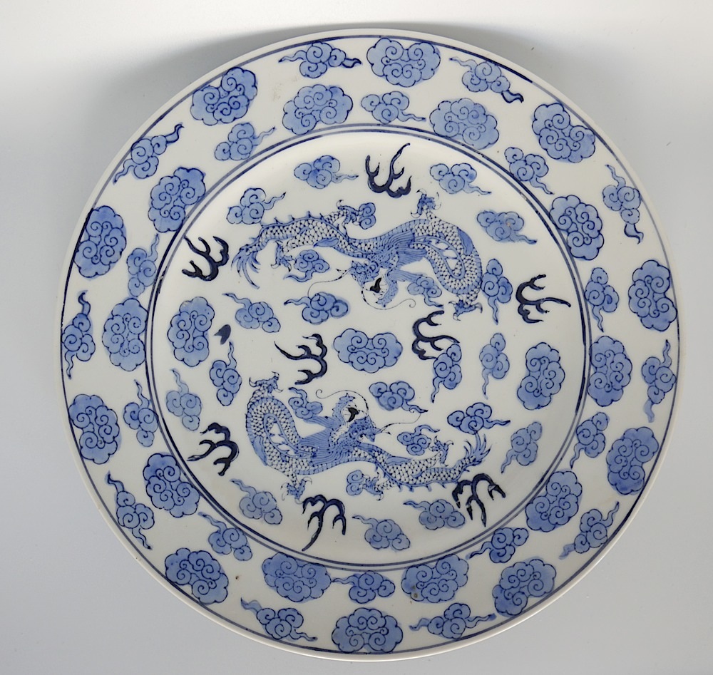 A Chinese blue & white plate decorated with two four-clawed dragons, on bat & cloud design ground